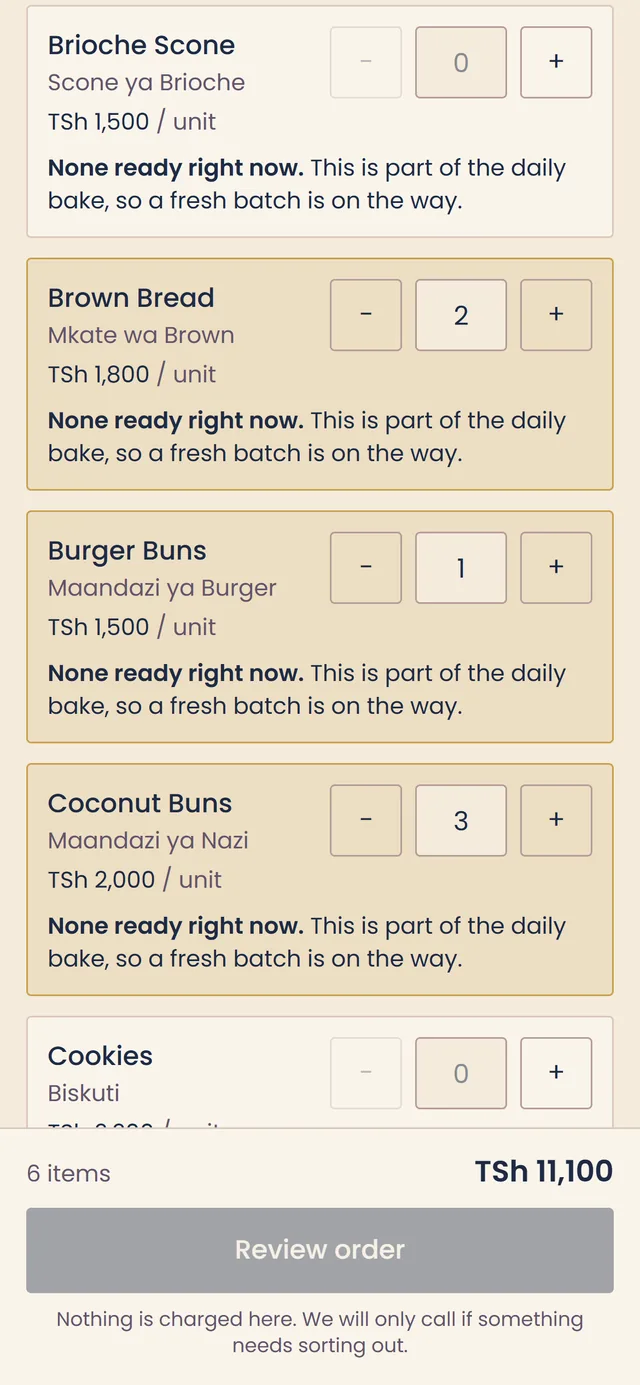 S&M Bakeries ordering app on a phone: brown bread, burger buns and coconut buns chosen and highlighted, with six items totalling TSh 11,100 in the footer